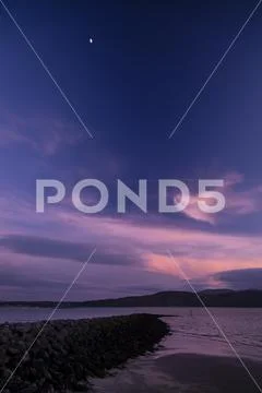 Moon and clouds over the North Wales coast at dusk Stock Photos
