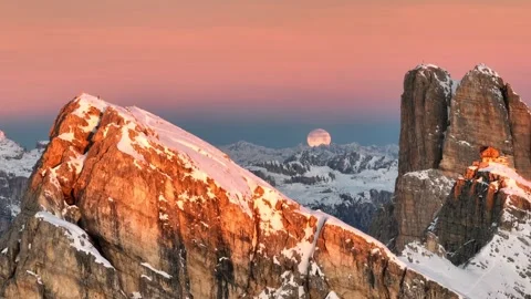 The moon appears from behind the snow covered mountains amid reflections, 4k Stock Footage 254584345