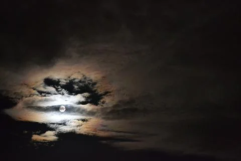 Moon behind clouds that makes the clouds shine Stock Photos