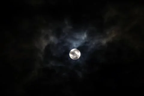 The Moon behind the clouds. The moon in a partially clouded colorful sky. Stock Photos