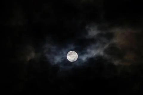 The Moon behind the clouds. The moon in a partially clouded colorful sky. Stock Photos