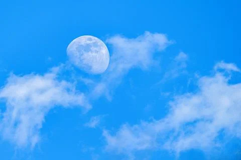Moon behind the clouds - sharp details on the surface. Stock Photos