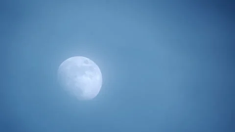 The moon behind moving thin clouds in the blue sky Stock Footage 333762454