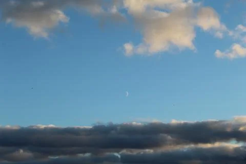 Moon between the clouds in the blue sky 写真素材