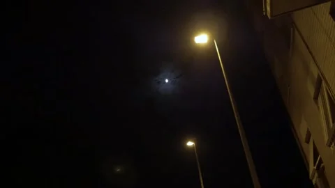 Moon clouds night lamp post streetlamps lights building windows Stock Footage 340896941