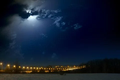 Moon with clouds in the night sky. Car highway lit lanterns. Landscape phot.. Stock Photos