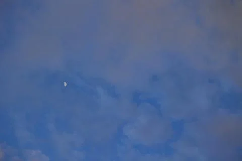 Moon on the cloudy sky before sunset Stock Photos