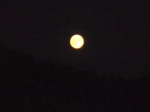 Moon in complete darkness with slightly yellow color tone. Stock Photos