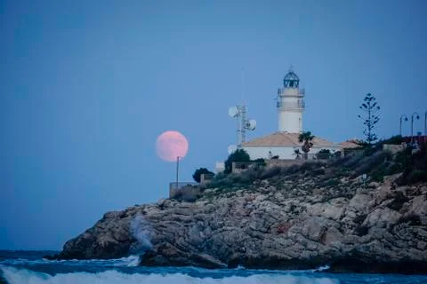 Moon eclipse over a lighthouse Stock Photos