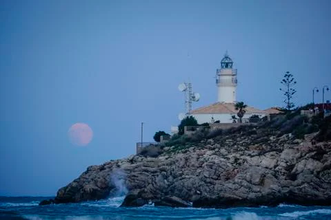Moon eclipse over a lighthouse Stock Photos