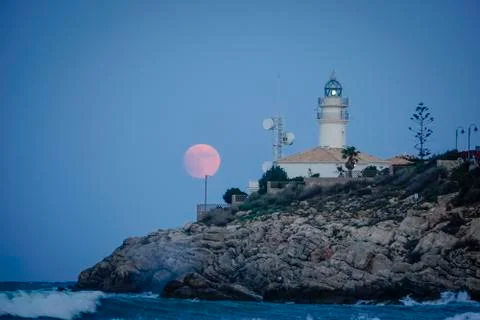 Moon eclipse over a lighthouse Stock Photos