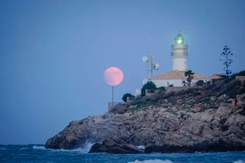 Moon eclipse over a lighthouse Stock Photos