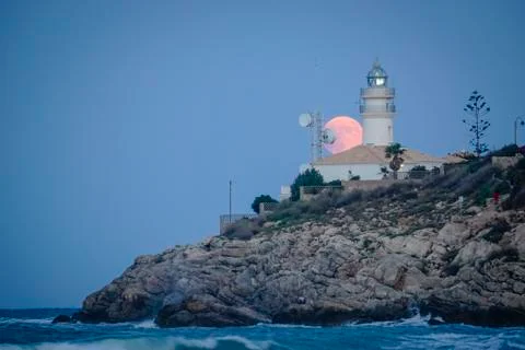 Moon eclipse over a lighthouse Stock Photos