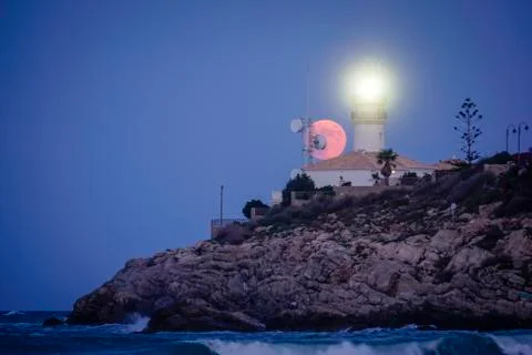 Moon eclipse over a lighthouse Stock Photos
