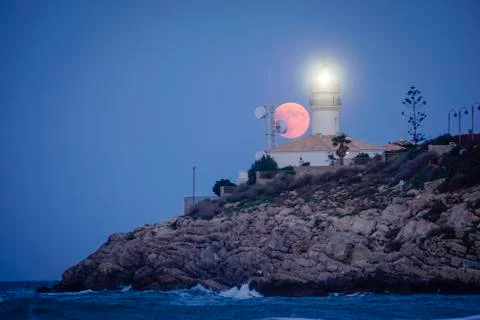 Moon eclipse over a lighthouse Stock Photos