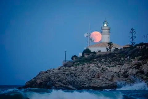 Moon eclipse over a lighthouse Stock Photos