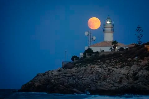 Moon eclipse over a lighthouse Stock Photos