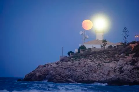 Moon eclipse over a lighthouse Stock Photos