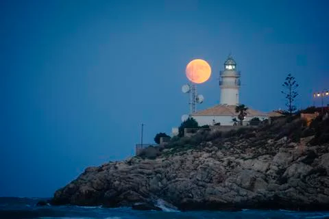 Moon eclipse over a lighthouse Stock Photos
