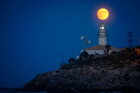 Moon eclipse over a lighthouse Stock Photos