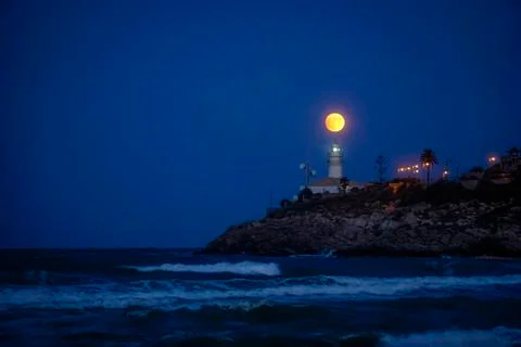 Moon eclipse over a lighthouse Stock Photos