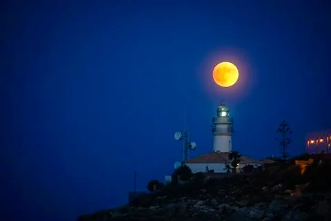 Moon eclipse over a lighthouse Stock Photos