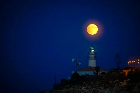 Moon eclipse over a lighthouse Stock Photos