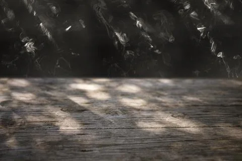 Moon light rays thru foliage at night, on weathered wood boards table, side.. Stock Photos