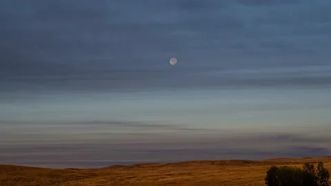 Moon moves behind thin clouds towards the horizon in this time lapse.  Stock Footage 209720868