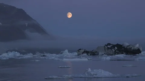 Moon over the Arctic Mountains and the ocean, Greenland Video stock 103575332