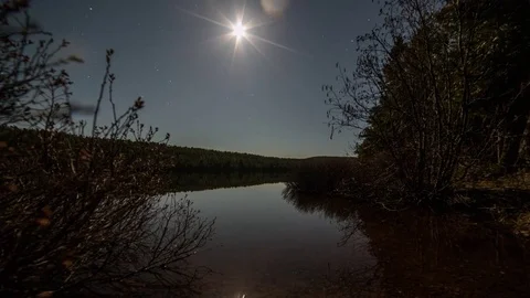 Moon over calm lake while clouds move in Stock Footage 72878923