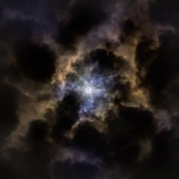 The Moon Partially Covered By Clouds in a Dark Night with Blue, Purple and Br Фото