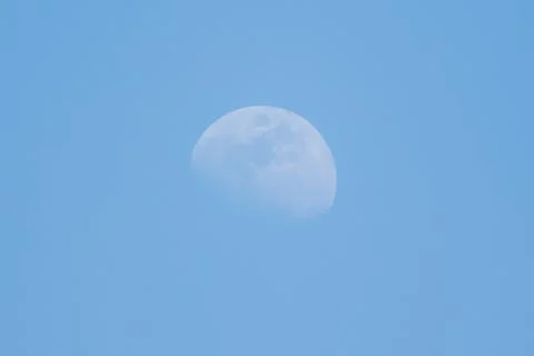 Moon phase shows crescent shape against blue sky background Stock Photos