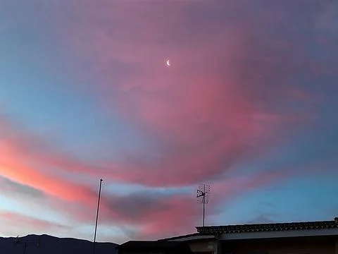 The moon in the pink clouds of dawn Stock Photos