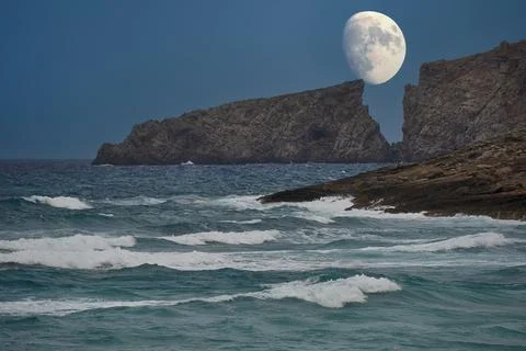 Moon rising between the cliffs of a Mediterranean beach Stock Photos