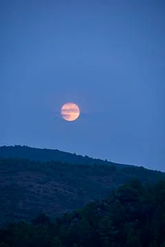 The moon rising between the mountains Stock Photos