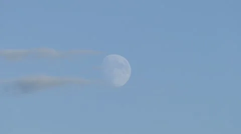 The moon rising in clear sky with clouds moving sideways slowly Stock Footage 43312931