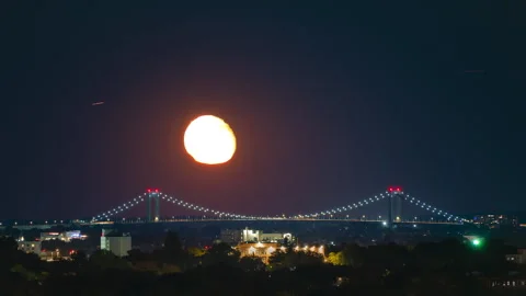 Moon rising over lighted suspension bridge in New York City. Stock Footage 319960692