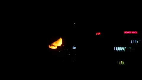 Moon Sets Behind Building Stock Footage 97968210