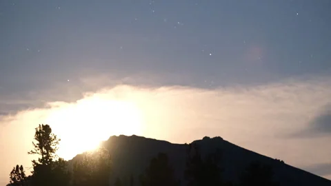 Moon setting behind a mountain ridge at dawn Video stock 300982313