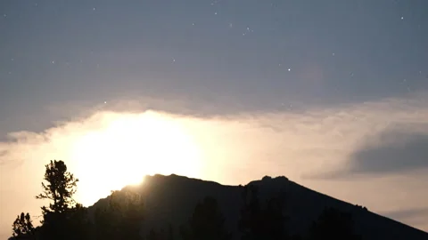 Moon setting behind a mountain ridge at dawn Stock Footage 300989854