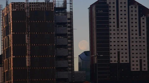 Moon setting between office buildings leeds uk Stock Footage 124637471