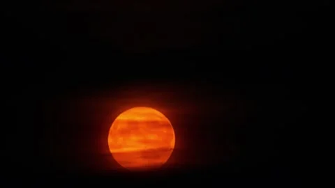 Moon setting beyond clouds illuminating orange glow Stock Footage 336728837