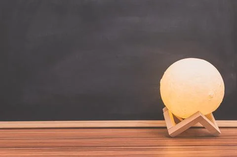 Moon shape lamp On the desk Blackboard background Stock Photos