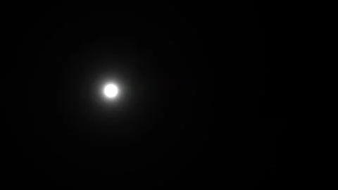 Moon shines brightly in a dark night sky above Stock Footage 338227160