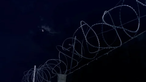 The moon shines through the barbed wire. Stock Footage 115328560