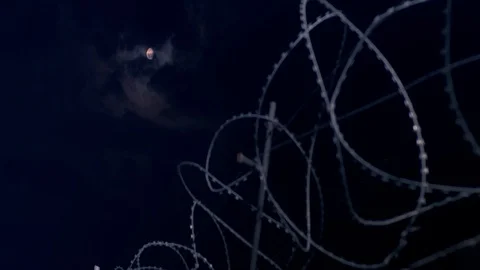 The moon shines through the barbed wire. Stock Footage 115333331