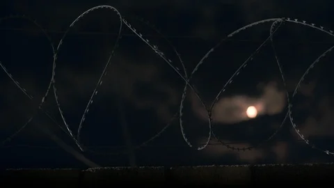 The moon shines through the barbed wire. Timelapce. Video stock 115333820