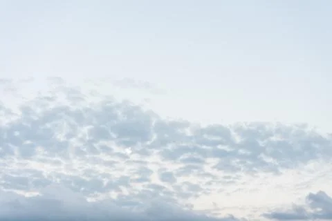 Moon shining through clouds at sunset Stock Photos