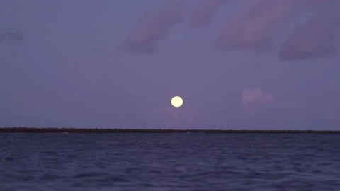 Moon sitting low over Sea with purple and blue sky and clouds Stock Footage 167012315